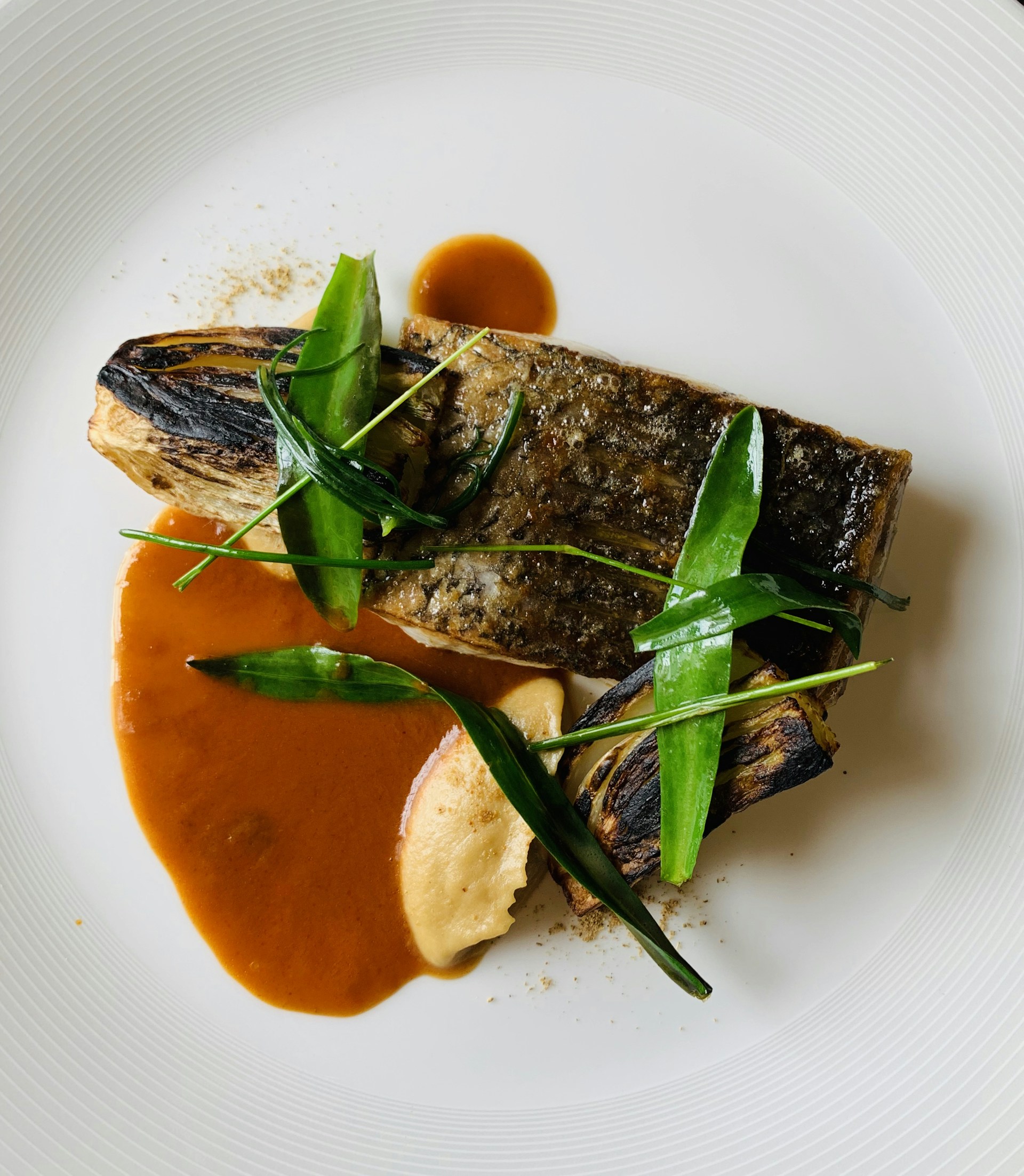 A delicious plate of fresh market fish, perfectly cooked and garnished, representing the Mediterranean cuisine.