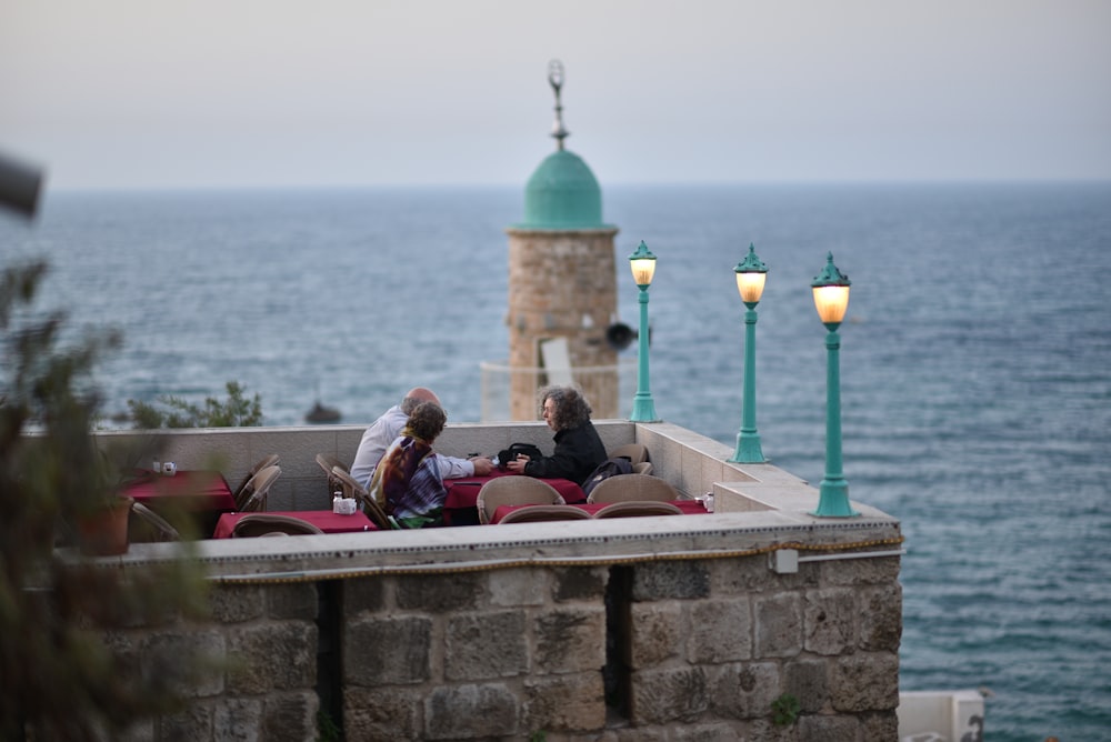 people dining on roof top of building near body of water