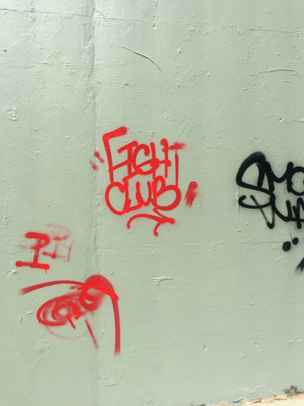 a white wall with some red and black graffiti on it