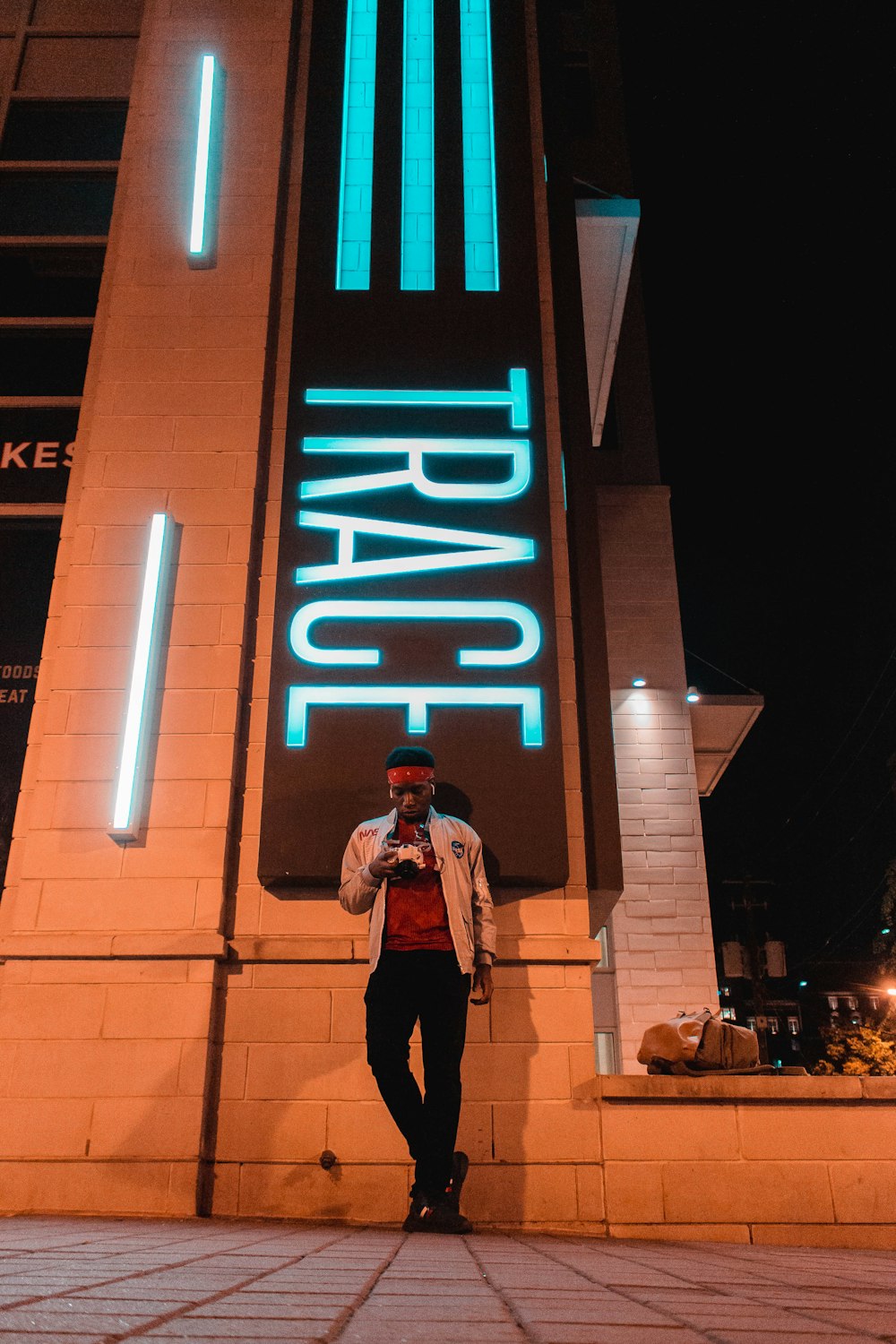 man standing under Trace signage