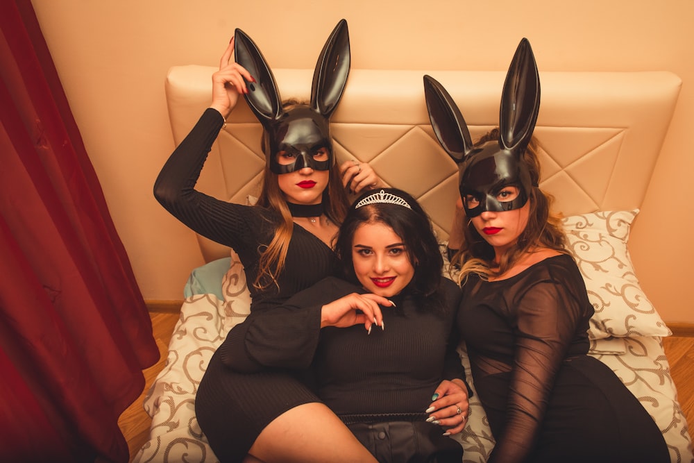 three women in bunny ears are sitting on a bed