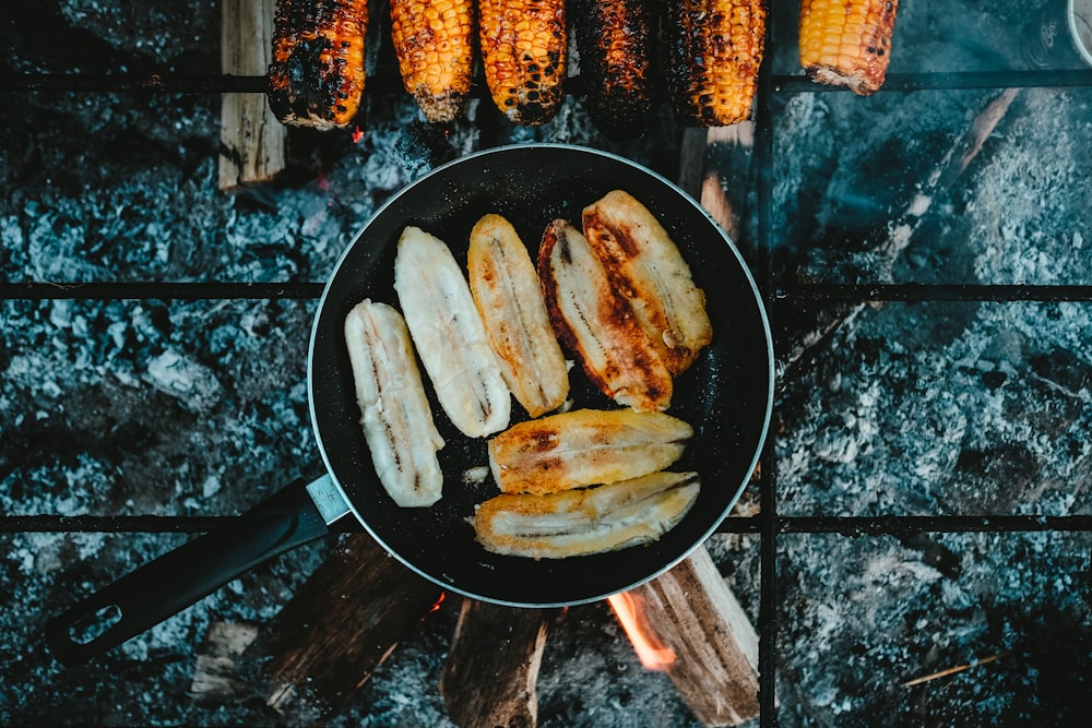 a frying pan filled with bananas and corn on the cob