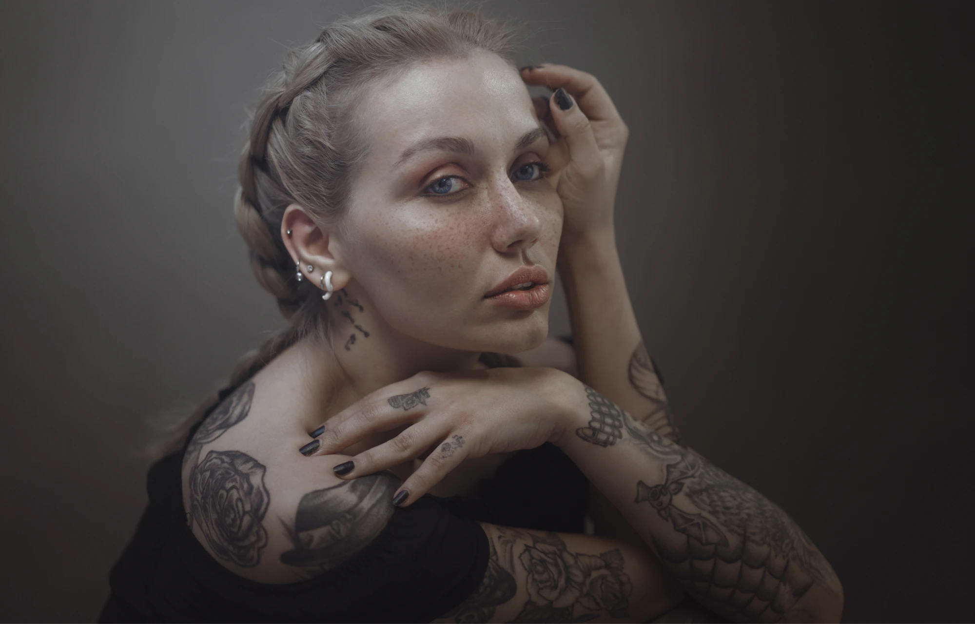 Tattooed model with braided hair and inked sleeves looking into the camera