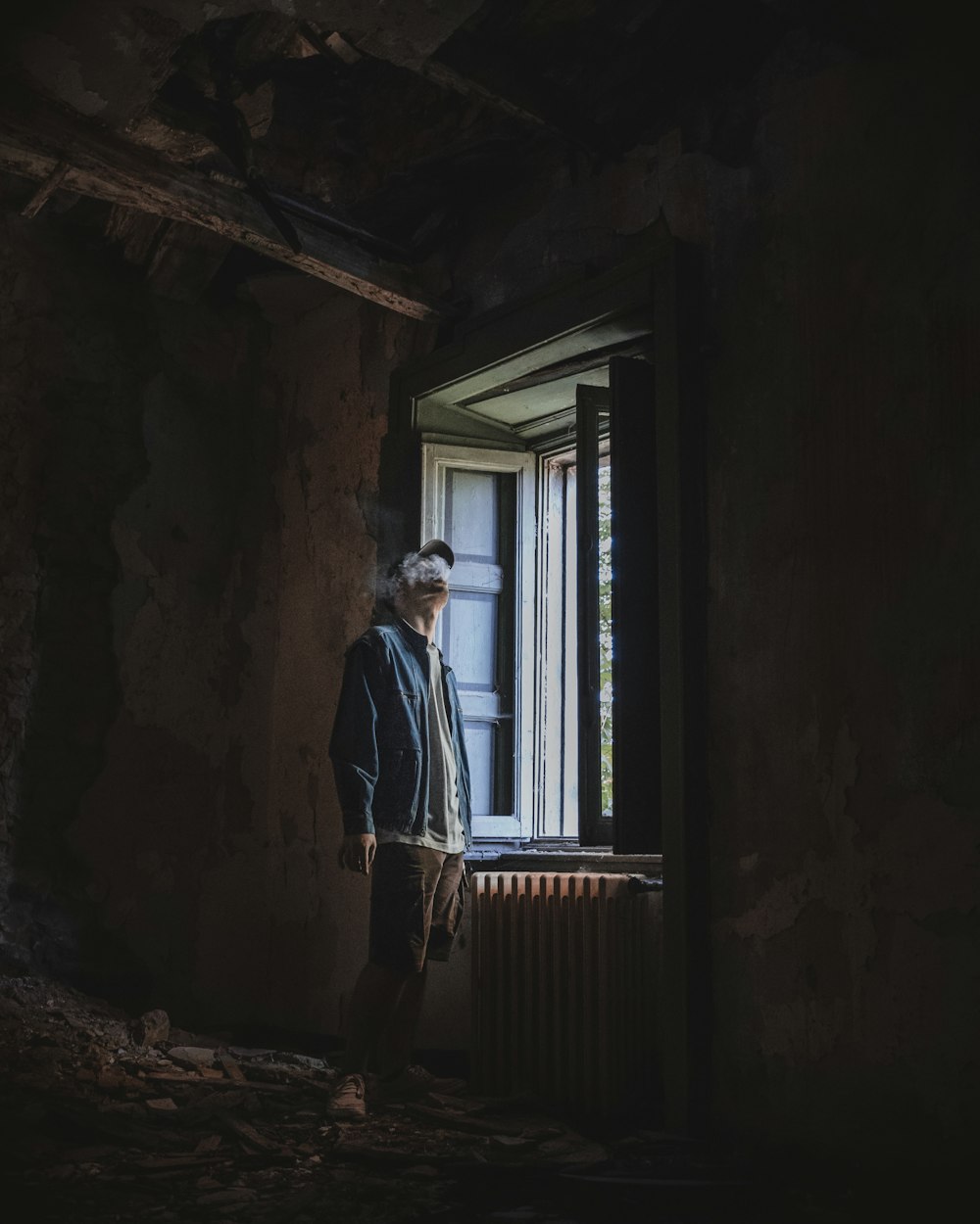 smoking man wearing jacket standing beside opened window