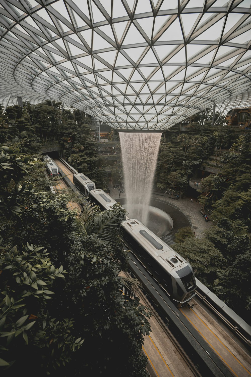 a train traveling through a train station next to a waterfall