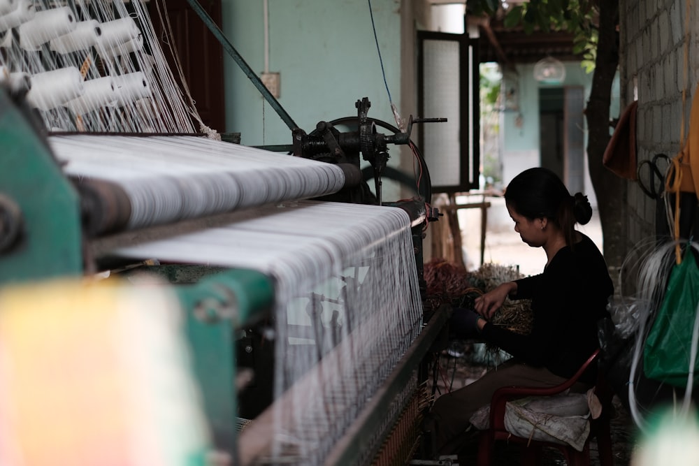 a woman sitting on a chair in front of a loom