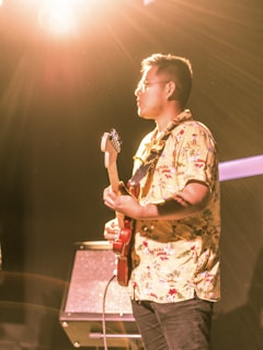 Close-up of a musician passionately playing guitar with yellow spotlights in the background.