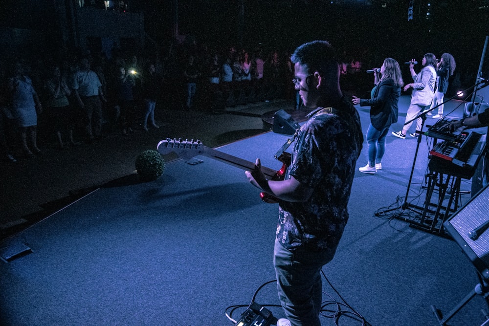 group of people playing individual instrument while performing on stage surrounded with people watching