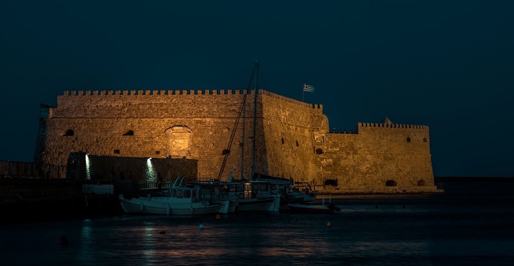 a night scene of a castle with boats in the water