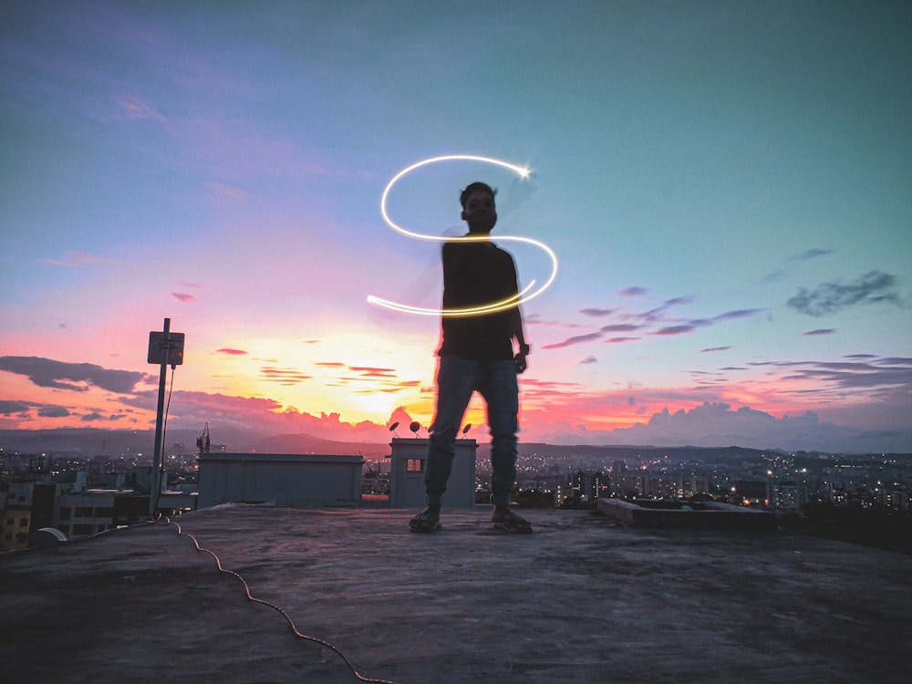 a man standing on top of a roof holding a hula hoop