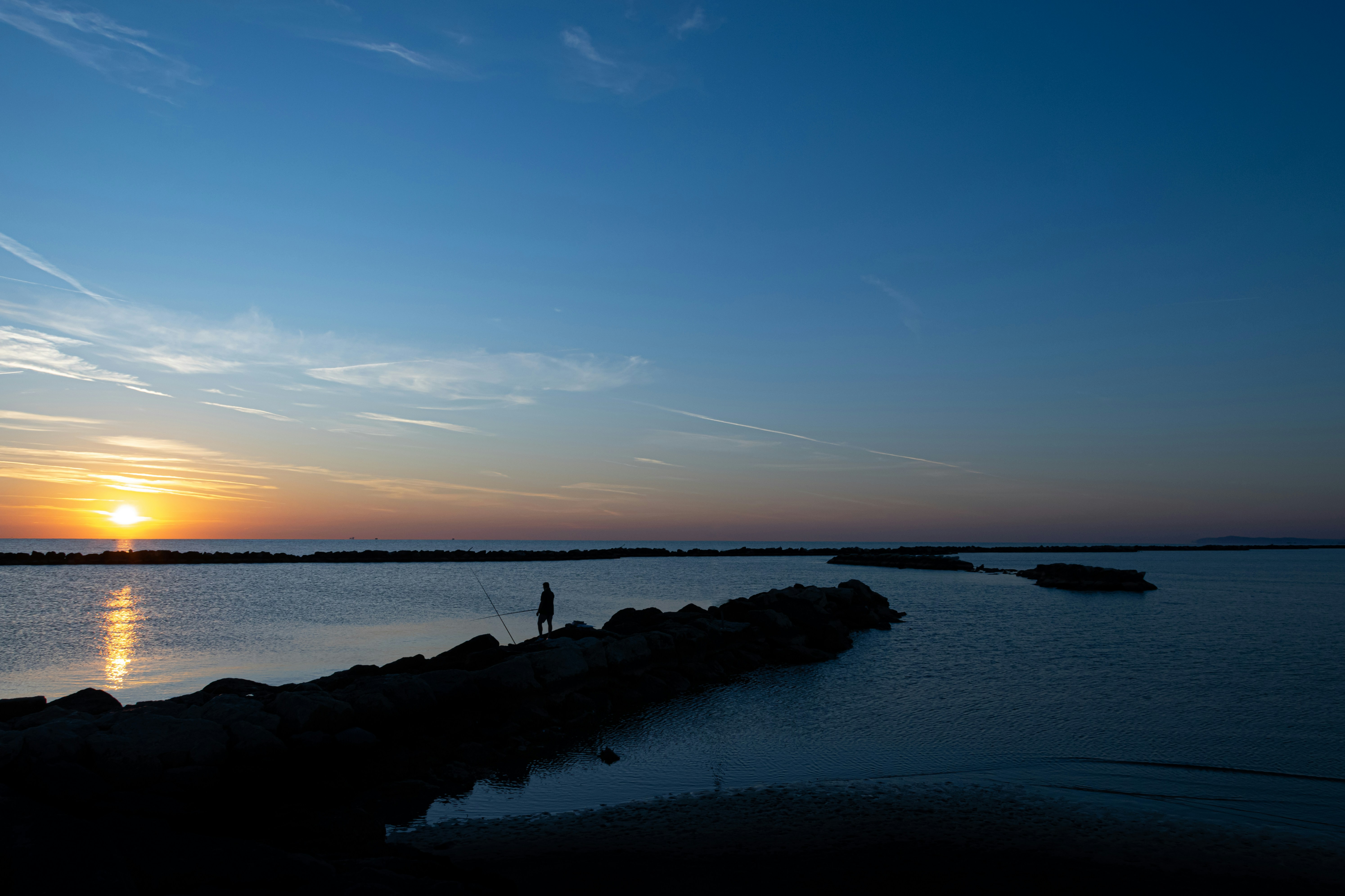 person standing on rocky dock during day