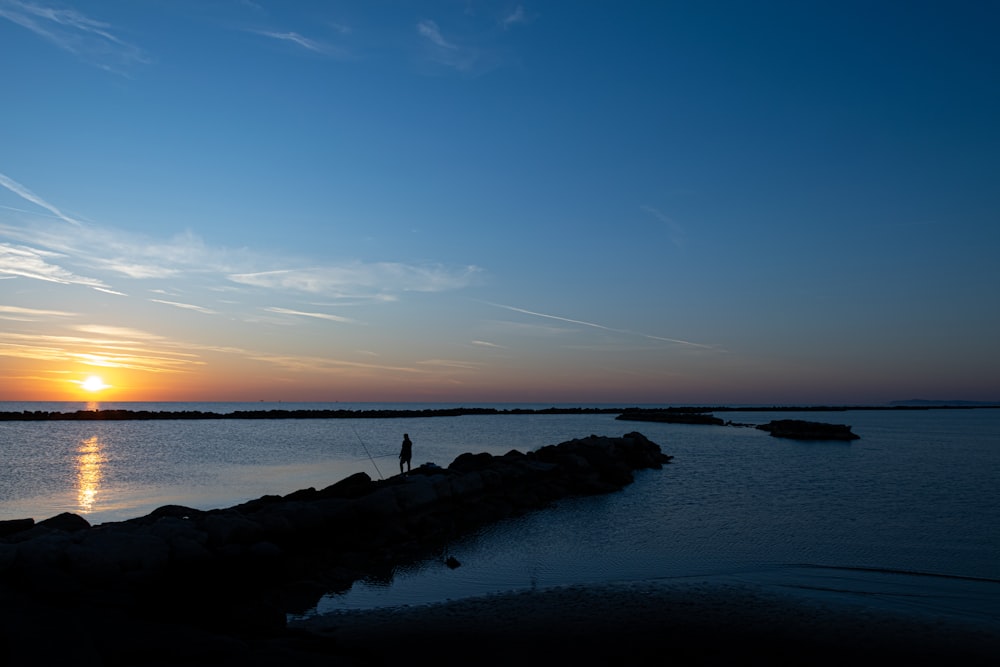 person standing on rocky dock during day