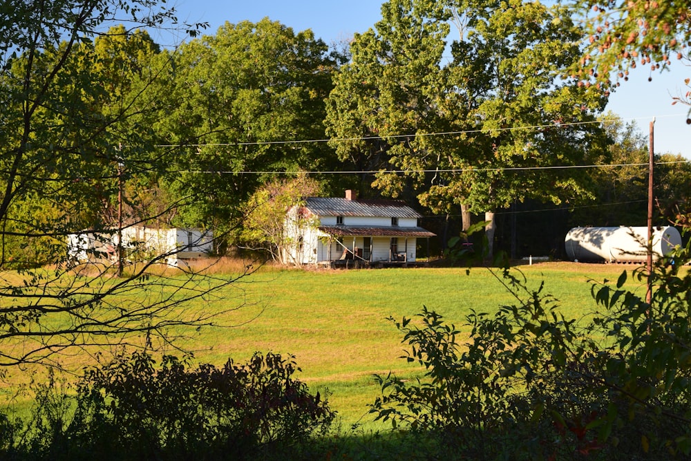 white and brown house surrounded by green-leafed trees and grass fields