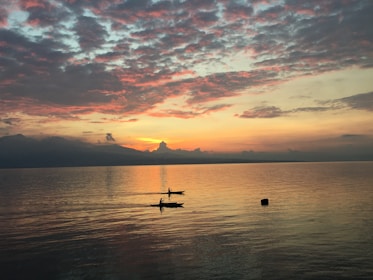 A serene beach at sunset with people kayaking.