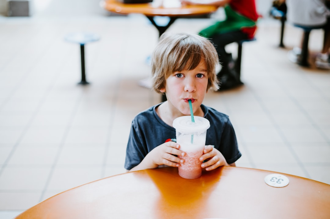 boy zipping beverage with straw in disposable cup