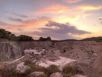 Panoramic view of a granite quarry with heavy machinery working under a golden sunset.