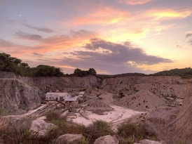A panoramic view of a quarry with trucks transporting Aswani clay during sunset.