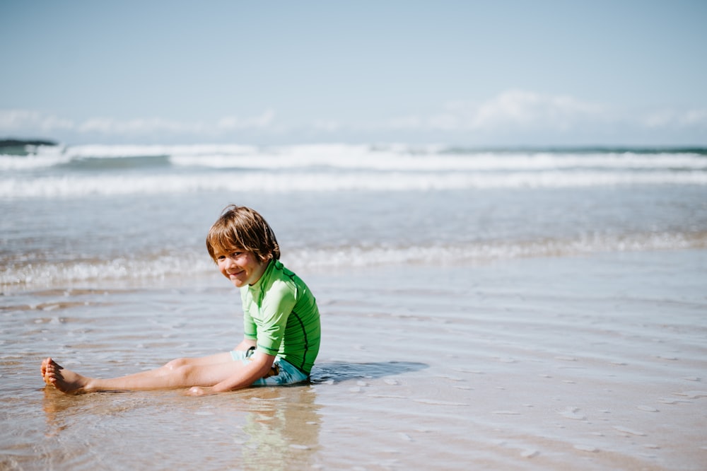 boy sitting on shore at daytime