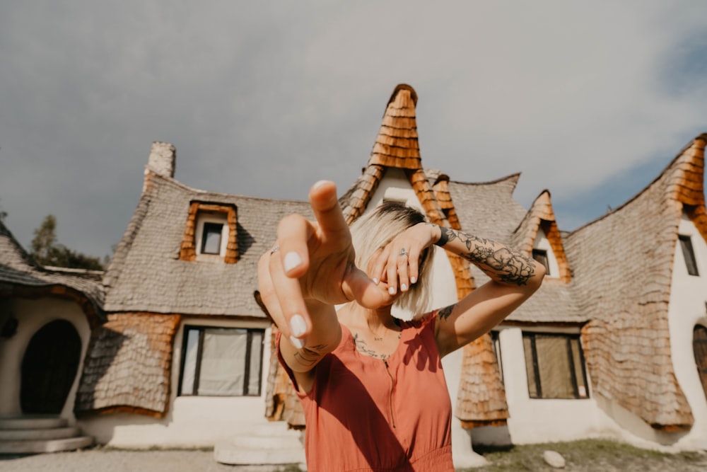 woman covering her face with her left hand and pointing forward with her right hand