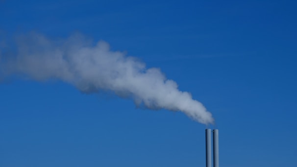 Industrial smokestacks with advanced emission control systems under a clear blue sky.