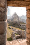 Machu Picchu ruins framed by a stone window with a mountain in the background
