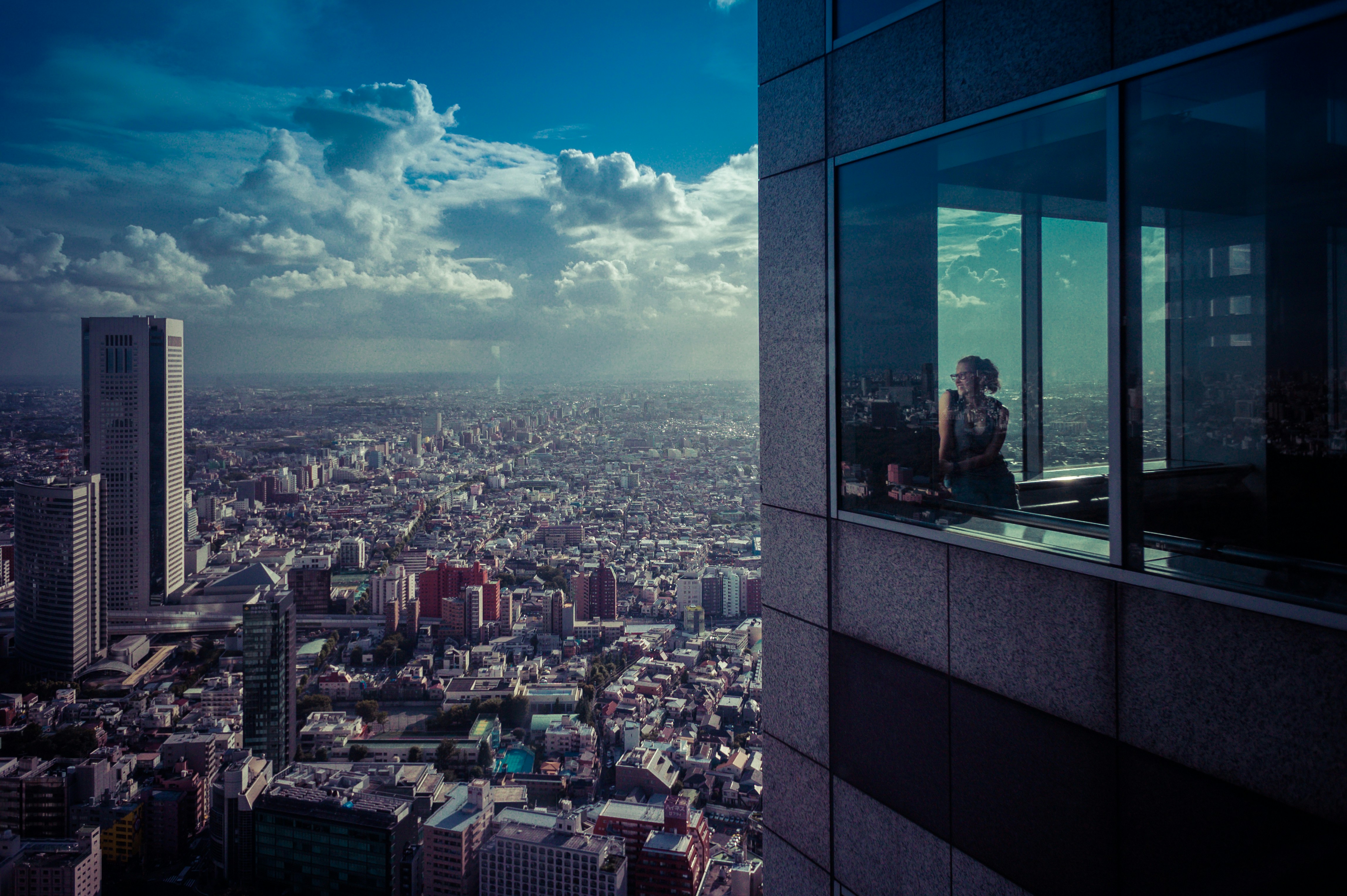 Girl looking to city from skyscraper