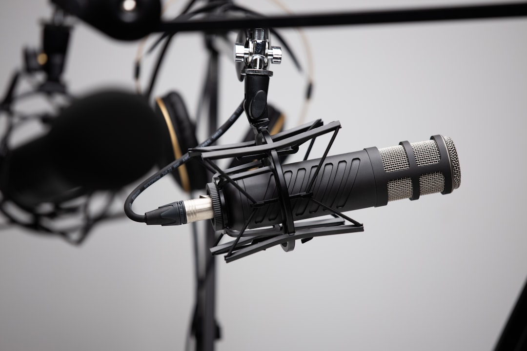 black and grey condenser microphone, Professional Podcasting mic and boom arms with headphones in the background