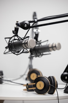 black and gold AKG corded headphones near black microphones