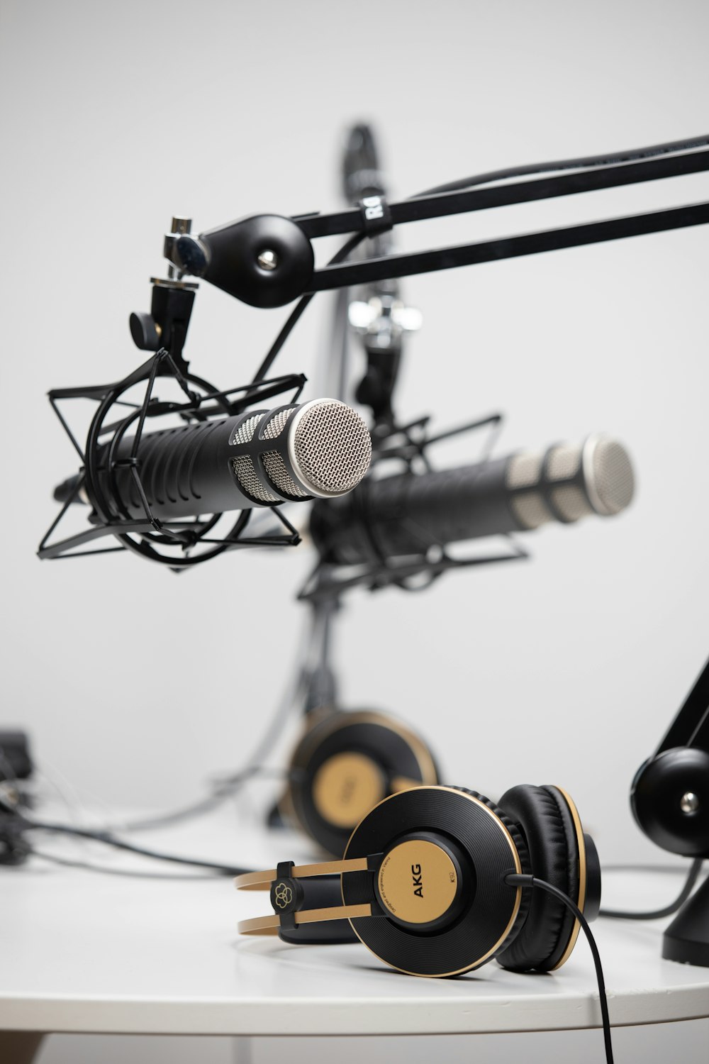 schwarze und goldene kabelgebundene AKG-Kopfhörer in der Nähe von schwarzen Mikrofonen