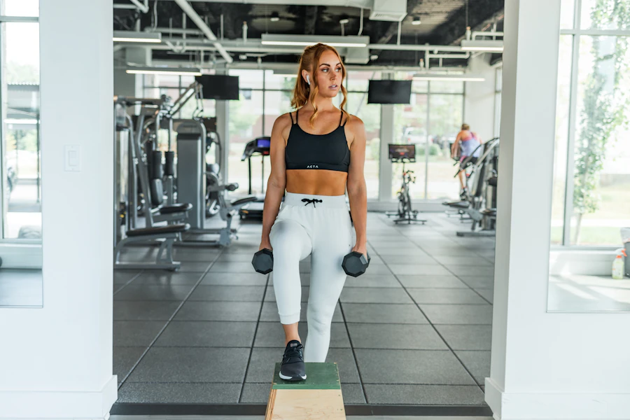 Mujer entrenando con mancuernas en un gimnasio moderno