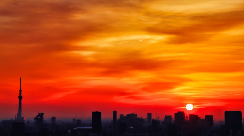 silhouette of city with high-rise buildings under orange skies