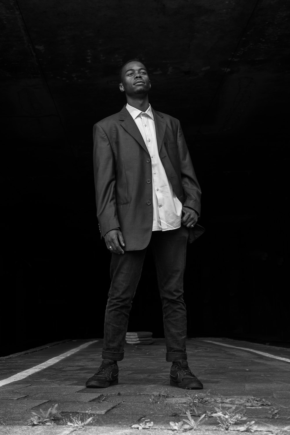 grayscale photography of standing man wearing suit