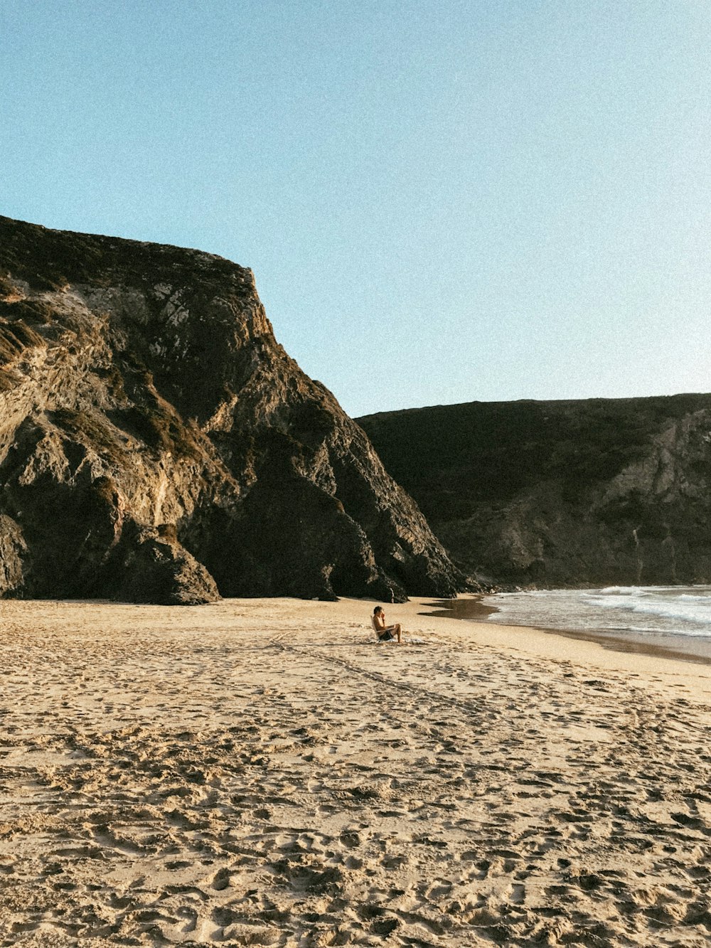 person sitting on seashore during daytime