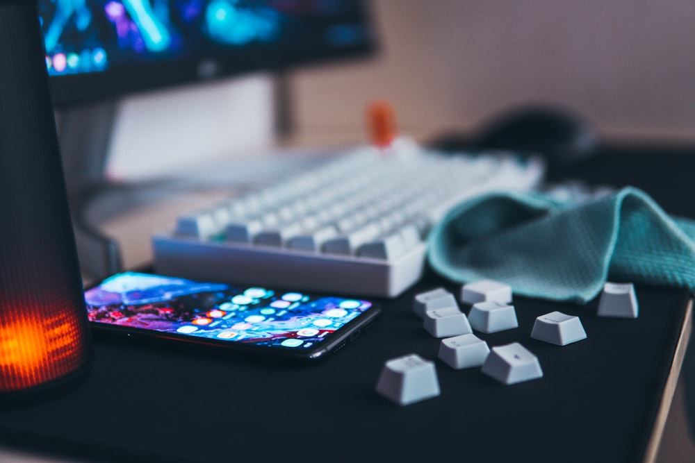 black Android smartphone beside keyboard and monitor