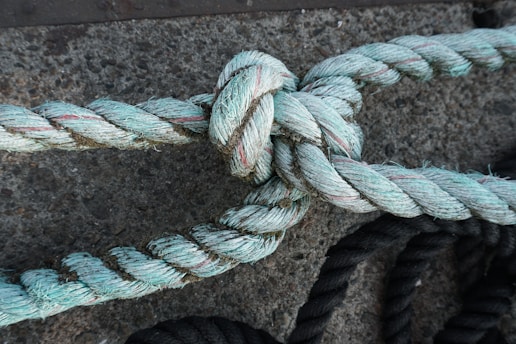 Close-up of a sturdy electrician’s knot tied around a thick conduit in an industrial setting.