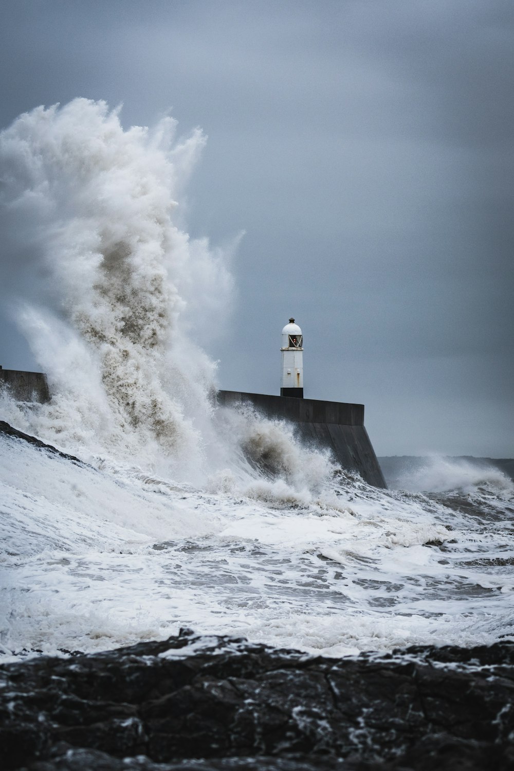 big waves crashing on lighthouse during daytime