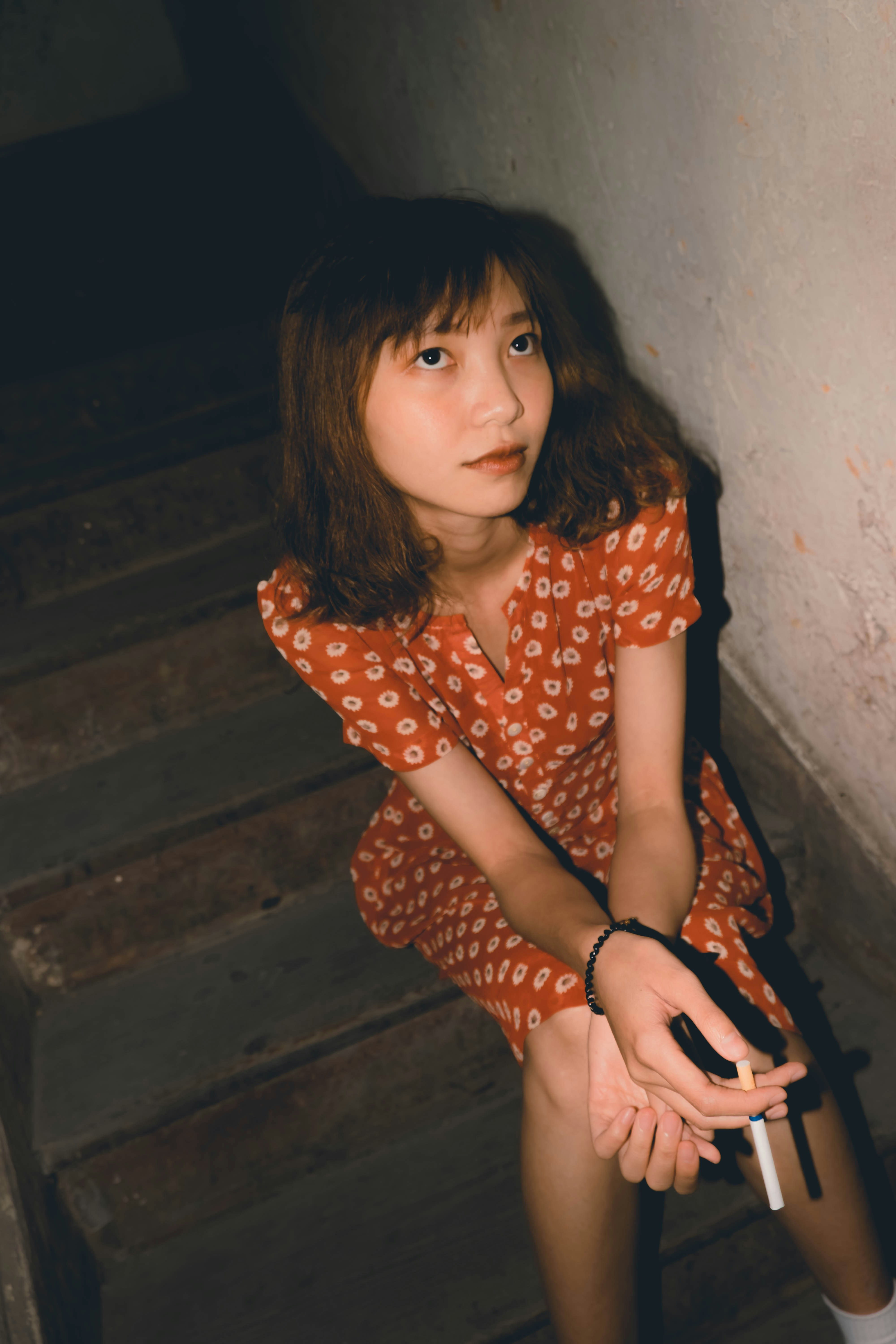 woman holding cigarette while sitting on stairs