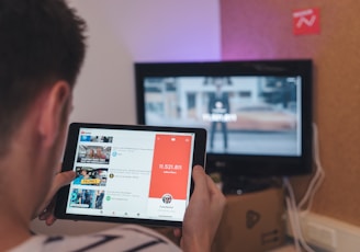 man browsing tablet sitting in front of TV