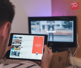 man browsing tablet sitting in front of TV