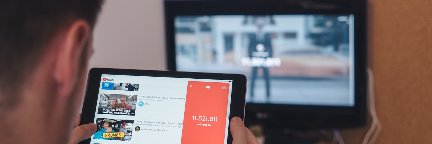 man browsing tablet sitting in front of TV