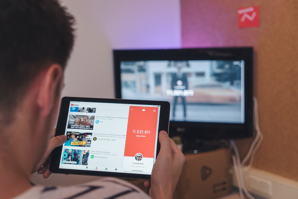 man browsing tablet sitting in front of TV