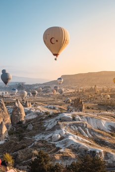 A vibrant sunrise over Cappadocia with colorful hot air balloons ascending above fairy chimneys.