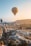A smiling couple enjoying a sunrise hot air balloon ride over Cappadocia's fairy chimneys.
