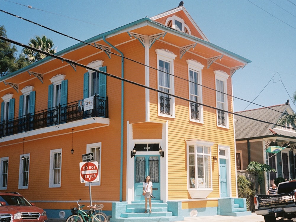 woman standing near orange 2-storey house