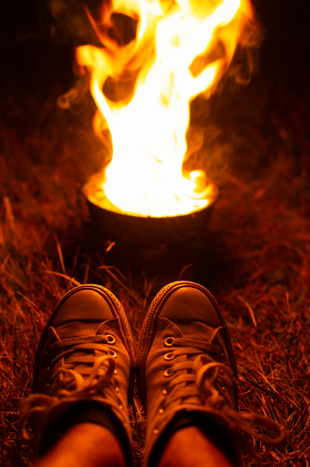 person wearing sneakers near fire in pot