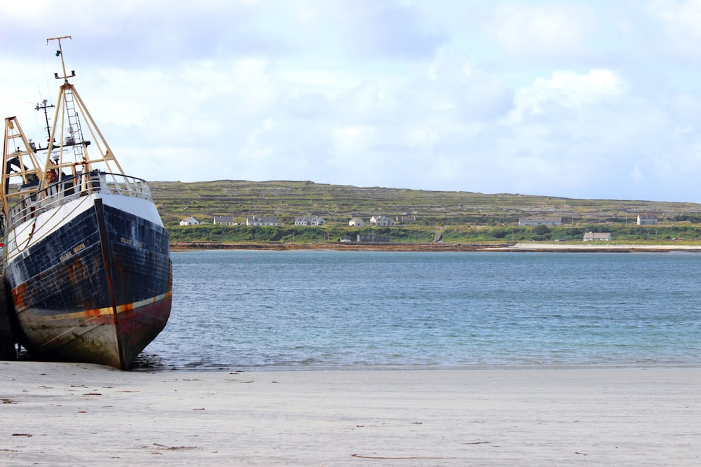 wrecked blue and white boat on shore at daytime