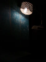 A pastoral woven wall lamp illuminating a textured wall with warm patterns.