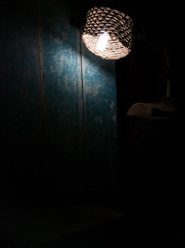 A pastoral woven wall lamp adding texture and warmth to a simple white wall.