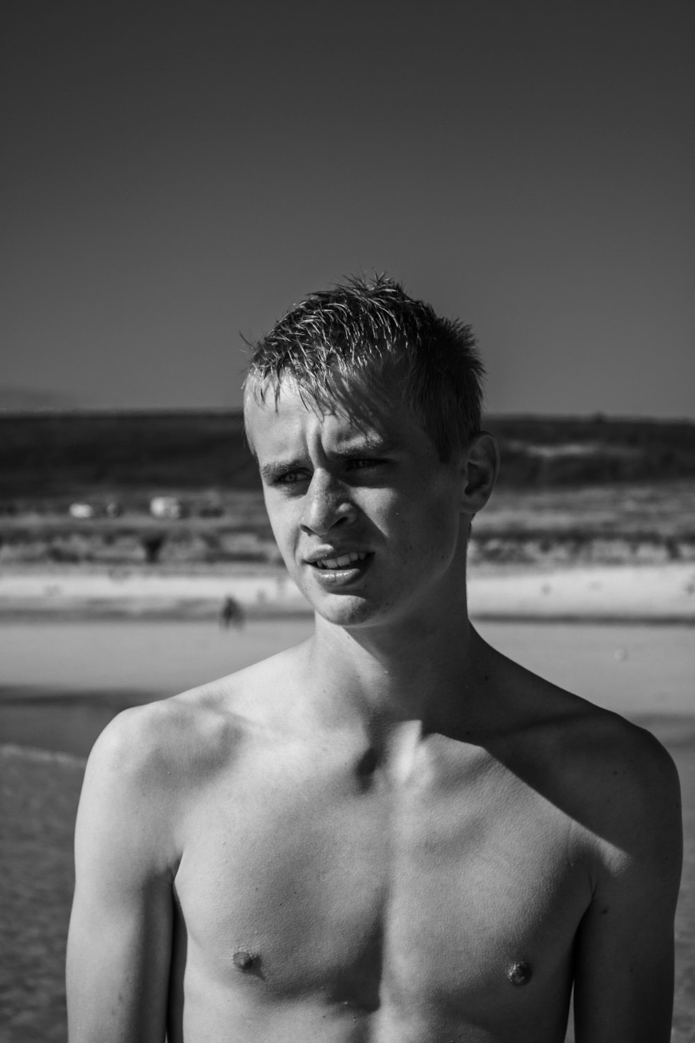 grayscale photography of man standing near shore