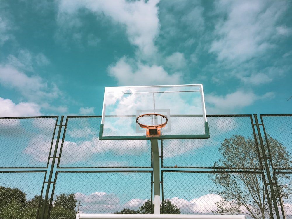 green and orange basketball hoop near green chain link fence under white  and blue skies during daytime photo – Free Blue Image on Unsplash